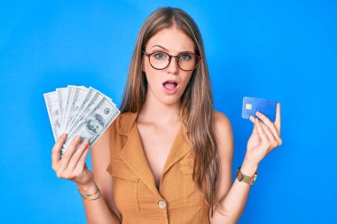 Genç sarışın kız kredi kartı ve dolar dolu bir yüzle kuşkucu, alaycı ve ağzı açık bir şekilde şaşırmış görünüyor. 