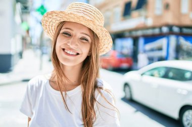 Genç sarışın kadın tatilde gülümsüyor. Mutlu bir şekilde caddede yürüyor.