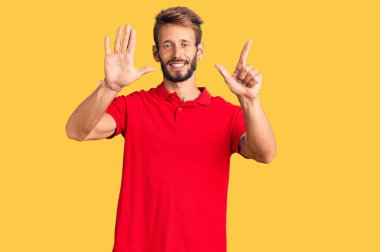 Yakışıklı, sakallı, günlük kıyafetler giyen, 7 numaralı parmaklarıyla gösteriş yapan, kendinden emin ve mutlu bir adam.. 