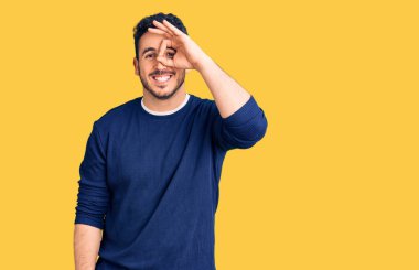 Gündelik kıyafetler giyen genç İspanyol adam el hareketleriyle gülümsüyor ve mutlu yüzüyle parmaklarından bakıyor.. 