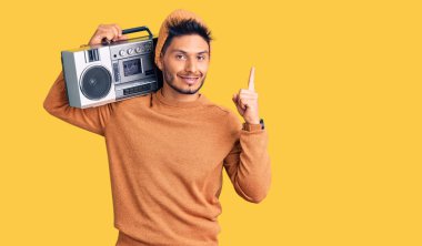 Yakışıklı Latin Amerikalı genç adam müzik kutusunu tutuyor, başarılı bir fikirle işaret eden müzik dinliyor. Heyecanlı ve mutlu. Bir numara.. 