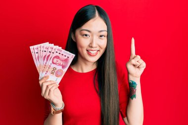 Genç Çinli kadın elinde 10 Yuan 'lık Çin banknotlarıyla bir fikir veya soru işareti ile gülümsüyor. 
