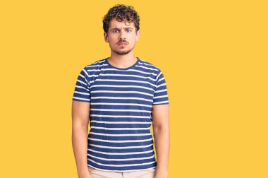 Kıvırcık saçlı, depresif giyinmiş, sıkıntıdan korkan sinirli ve korkmuş genç yakışıklı bir adam. hüzünlü ifade. 