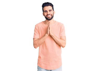 Sakallı, sıradan tişörtlü, elleri birarada dua eden, affedilmek isteyen, kendine güvenen genç yakışıklı bir adam.. 