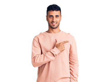 Gündelik kıyafetler giyen, neşeli, yüzünde gülümseme olan genç İspanyol adam mutlu ve doğal bir ifadeyle elini ve parmağını kaldırdı. 