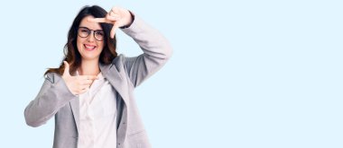 İş kıyafetleri ve gözlük takan, gülümseyen, elleri ve parmakları mutlu yüzlü güzel esmer kadın. yaratıcılık ve fotoğrafçılık kavramı. 