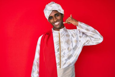 Geleneksel Sherwani elbisesi giyen yakışıklı Hintli adam telefonla el ve parmak hareketleriyle gülümsüyor telefonda konuşuyor gibi. iletişim kavramları. 