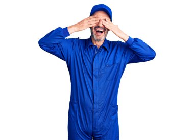 Orta yaşlı, yakışıklı, tamirci üniforması giyen, elleri gülücüklü, neşeli gözleri olan bir adam. kör kavram. 