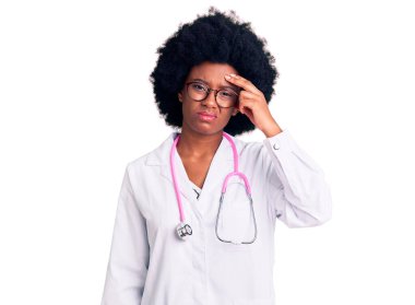 Doktor önlüğü ve steteskop giyen genç Afro-Amerikan kadın. Alnındaki sorun yüzünden endişeli ve stresli. Kriz konusunda endişeli. 