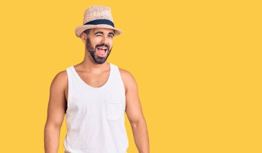 Gündelik yaz şapkası takan genç İspanyol adam kameraya seksi bir ifadeyle bakıyor, neşeli ve mutlu bir yüz.. 