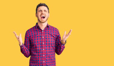 Ayılı yakışıklı genç adam, rahat gömleğini giyiyor deli gibi bağırıyor ve agresif bir ifadeyle bağırıyor ve kollarını kaldırıyor. hüsran kavramı. 