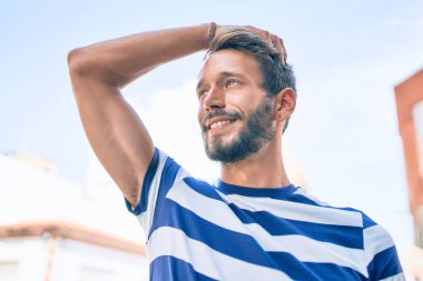 Sakallı yakışıklı beyaz adam, dışarıda mutlu bir şekilde gülümsüyor.