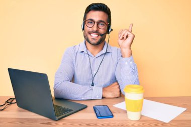 Çağrı merkezindeki operatör kulaklığı takmış, masada oturan genç İspanyol adam mutlu bir şekilde elini ve parmağını yana doğru uzatıyordu. 