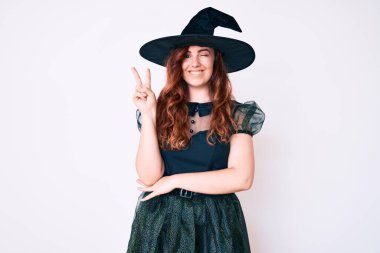 Cadı cadılar bayramı kostümü giyen genç ve güzel bir kadın kameraya gülümseyen ve parmaklarıyla zafer işareti yapan. İki numara.. 