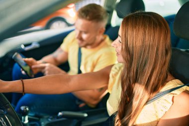 Mutlu bir şekilde gülümseyen genç çift ve GPS akıllı telefonu kullanıyorlar..