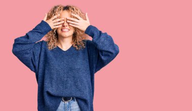 Kıvırcık saçlı, sıradan bir süveter giyen, elleri gülücüklü, neşeli ve komik gözleri olan genç sarışın kadın. kör kavram. 