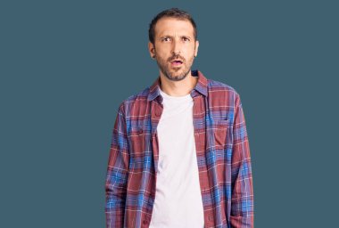 Şok olmuş gibi giyinmiş, kuşkucu ve alaycı görünen, ağzı açık genç ve yakışıklı bir adam. 