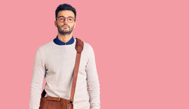 Yüzünde ciddi bir ifade olan deri çanta giyen yakışıklı bir İspanyol. Basit ve doğal bir şekilde kameraya bakıyorsun.. 