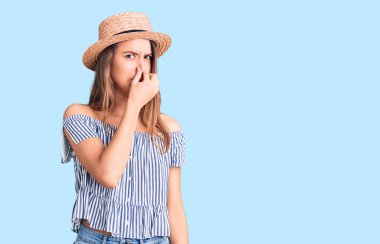 Şapka ve tişört giyen genç güzel bir kız pis ve iğrenç bir koku alıyor. Nefesini burnunda tutuyor. Kötü kokuyor. 