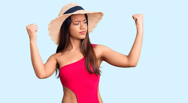 年轻美丽的拉丁女孩穿着泳衣 戴着夏帽 露出臂膀肌肉 微笑着感到自豪 健身概念 — 图库照片