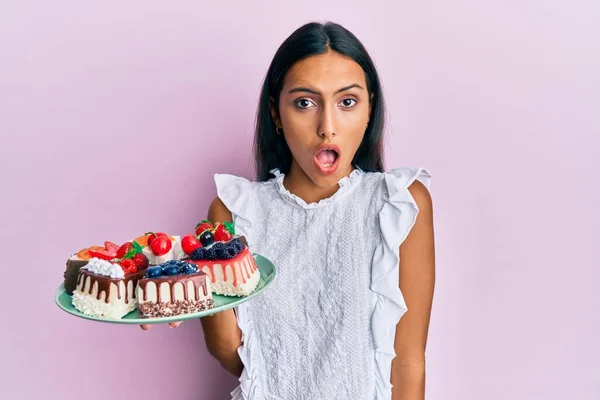 Young Brunette Woman Holding Cake Slices Scared Amazed Open Mouth — Stock Photo, Image