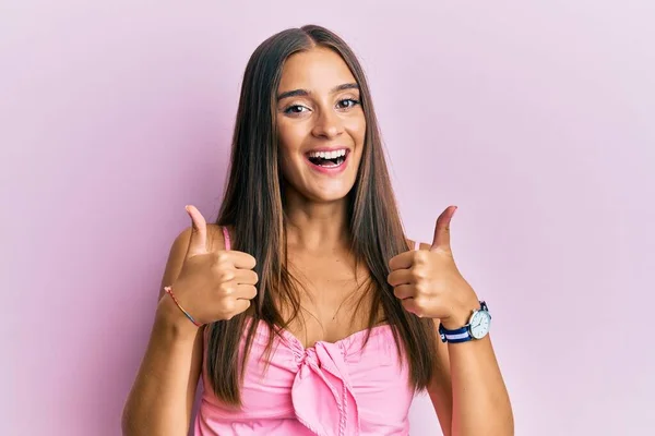 袖のないシャツの成功サインでカジュアルなスタイルを身に着けている若いヒスパニック系の女性は 手で積極的なジェスチャーを行う 親指を笑顔と幸せ 陽気な表情と勝者のジェスチャー — ストック写真