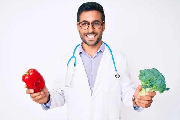 Jovem Hispânico Vestindo Estetoscópio Médico Segurando Pimenta Vermelha Brócolis Sorrindo — Fotografia de Stock