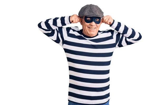 Hırsız Maskesi Tişörtü Giyen Yakışıklı Bir Adam Gülümsüyor Kulakları Parmaklarıyla — Stok fotoğraf
