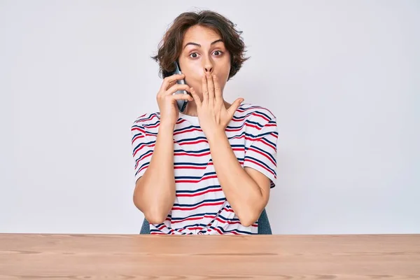 Ung Latinamerikansk Kvinna Talar Smartphone Sitter Bordet Täcker Munnen Med — Stockfoto
