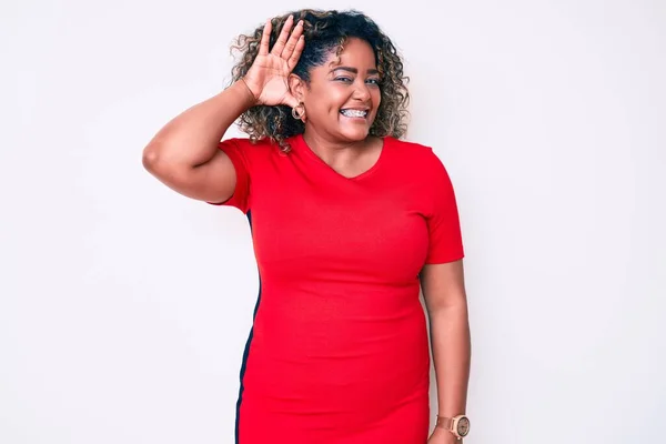 Young african american plus size woman wearing casual clothes smiling with hand over ear listening an hearing to rumor or gossip. deafness concept.
