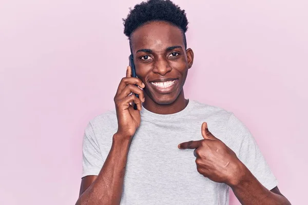 Young african american man having conversation talking on the smartphone pointing finger to one self smiling happy and proud