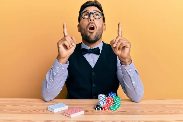 Poker Fişleri Kartlarıyla Masada Oturan Yakışıklı Spanyol Krupiyesi Şaşırmış Şaşırmış — Stok fotoğraf