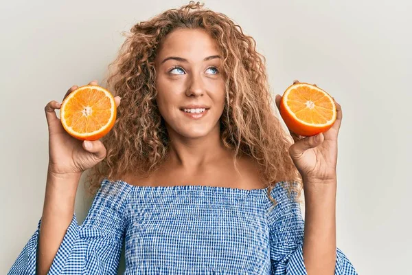 美丽的高加索少女 抱着新鲜的橙子 面带微笑地看着旁边 目不转睛地想着 — 图库照片