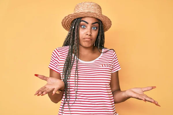 夏の帽子をかぶった若いアフリカ系アメリカ人女性は 腕や手を上げて混乱した表情をしています 疑わしい概念 — ストック写真