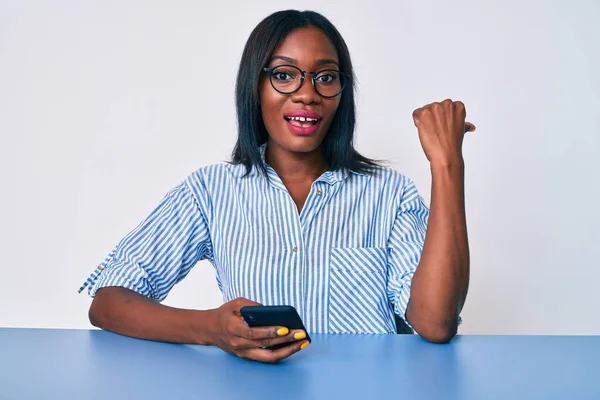 Молодая Африканская Американка Помощью Смартфона Сидит Столе Указывая Пальцем Вверх — стоковое фото