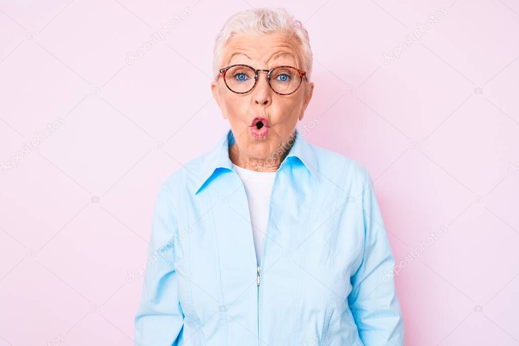 Senior beautiful woman with blue eyes and grey hair wearing glasses scared and amazed with open mouth for surprise, disbelief face 