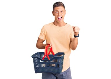Yakışıklı İspanyol adam elinde süpermarket alışveriş sepeti tutarak gururla bağırıyor zaferi ve başarıyı kutluyor. Kollarını kaldırıp heyecanla bekliyor. 