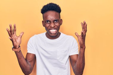 Genç, Afro-Amerikan bir adam günlük giysiler içinde öfkeyle bağırıyor, elleri boğmaya çalışıyor, deli gibi bağırıyor. 