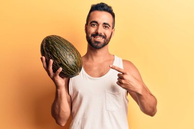 Karpuz tutan genç İspanyol adam gülümsüyor. 