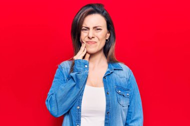 Genç ve güzel bir kadın diş ağrısı ya da diş hastalığından dolayı ağızlarına acı dolu bir ifadeyle dokunuyor. dişçi 