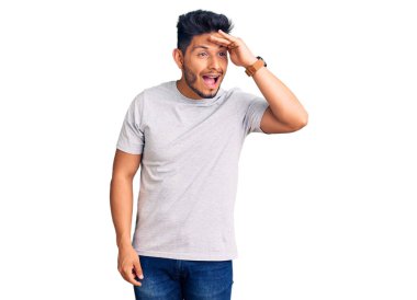 Yakışıklı Latin Amerikalı genç adam gündelik tişört giyiyor çok mutlu ve gülümsüyor başlarını kaldırıp uzaklara bakıyor. arama kavramı. 