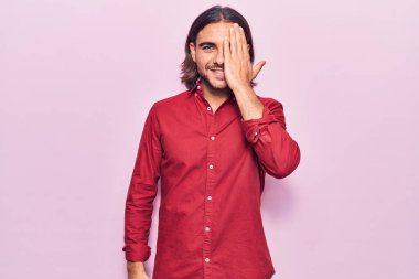 İş kıyafetleri giyen genç yakışıklı bir gözünü eliyle kapatıyor, yüzünde kendine güvenen bir gülümseme ve şaşırtıcı bir duygu var.. 