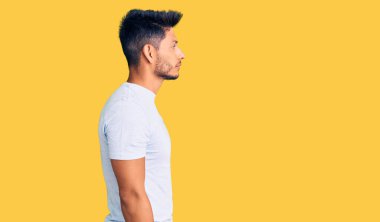 Yakışıklı Latin Amerikalı sıradan kıyafetler giyen rahat profil pozu veren, kendine güvenen gülümseyen genç adam.. 