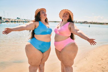 İki kilolu şişman ikiz kız kardeş. Yaz tatilinde sahilde yürüyen mutlu ve gururlu kadınlar.