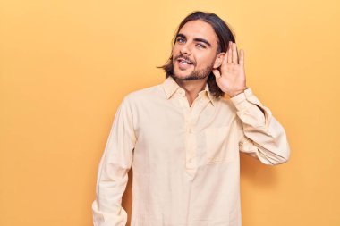 İş kıyafetleri giymiş genç yakışıklı bir adam kulağına fısıldayarak dedikodu ya da dedikoduları dinliyor. Sağırlık kavramı. 