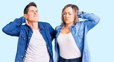 Sıradan kıyafetler giyen, boynu ağrıyan, elleriyle boynuna dokunan, kas ağrısı çeken iki kadın. 