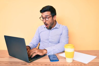 Genç İspanyol bir adam ofiste çalışıyor. Bir fincan kahve içiyor. Korkmuş ve şaşkın bir şekilde ağzı açık bekliyor. 