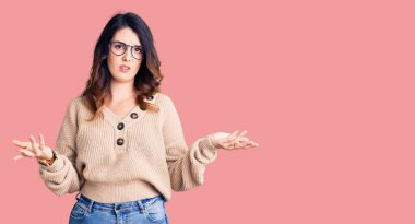 Güzel, genç, esmer bir kadın. Sıradan kıyafetler ve gözlük takıyor. Hiçbir şeyden habersiz ve kolları açık, hiçbir fikri yok.. 