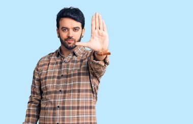 Günlük kıyafetler giyen genç İspanyol adam avucunun içi gibi şarkı söylemeyi kesiyor. Yüzünde olumsuz ve ciddi bir jest olan uyarı ifadesi. 