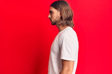 Sıradan kıyafetler giyen genç yakışıklı bir adam, rahat bir görünüm takınıyor kendine güvenen bir gülümsemeyle doğal bir yüz ifadesi takınıyor.. 